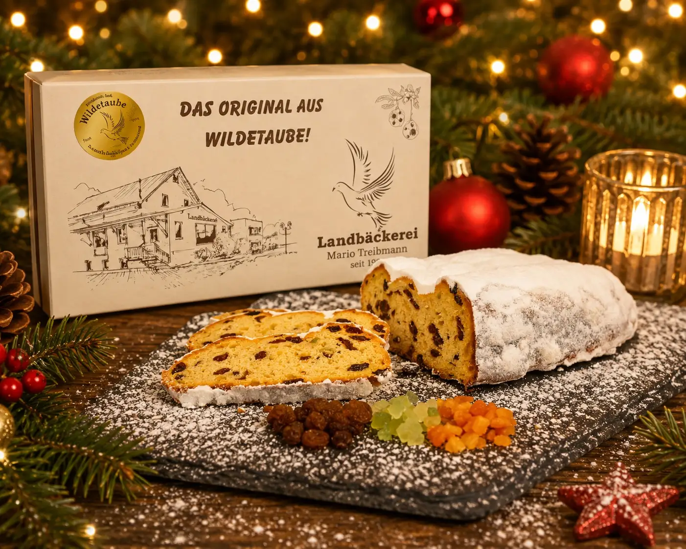 Cremefarbener Schmuckkarton mit goldenem Siegel, davor aufgeschnittener Butterstollen auf einer Schieferplatte